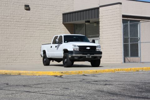2006 Chevrolet Silverado 2500 - A white Chevrolet Silverado pickup truck is parked in front of a building. The grille and headlights indicate it is from the mid-2000s.