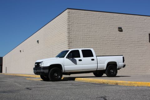2006 Chevrolet Silverado 2500 - A white 2006 Chevrolet Silverado 2500 pickup truck is parked on the side of a building.