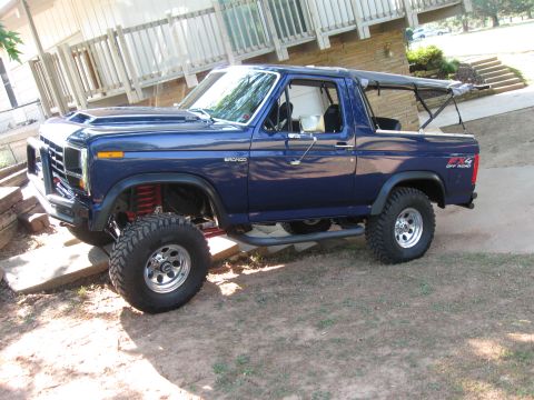 1982 Ford Bronco - This modified Ford Bronco features a lifted suspension and aggressive off-road tires, suggesting a model year around the early 1980s.