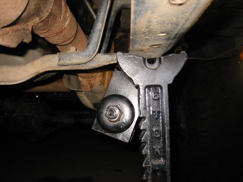 1985 Ford Bronco - Vehicle undercarriage supported by a jack stand, with visible exhaust pipes and frame components.