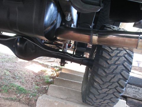 1982 Ford Bronco - The rear axle, fuel tank, and exhaust system are visible from underneath the vehicle.