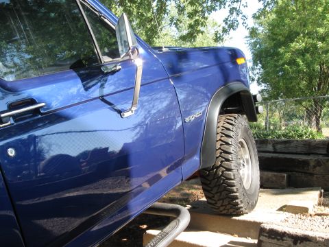 1982 Ford Bronco - A blue Ford Bronco with prominent off-road tires is parked outdoors.