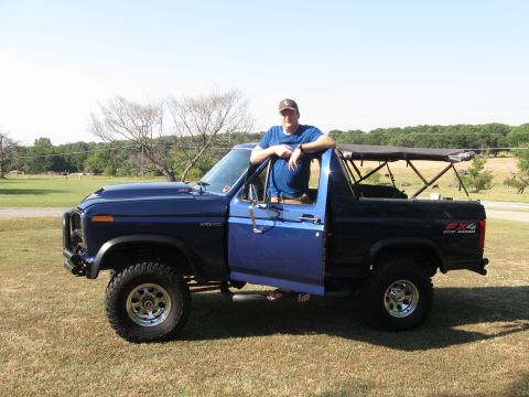 1982 Ford Bronco - A man poses with his blue 1982 Ford Bronco, which features an FX4 off-road decal on the rear fender.