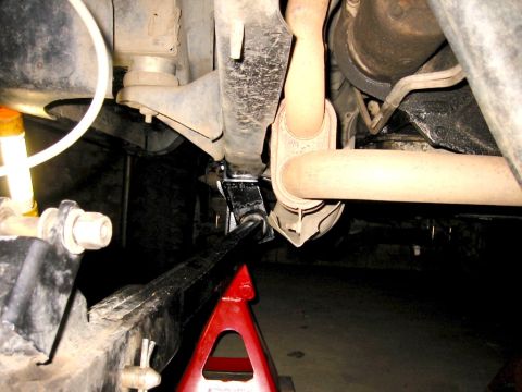 1985 Ford Bronco - The underside of a vehicle is visible, supported by jack stands for maintenance.