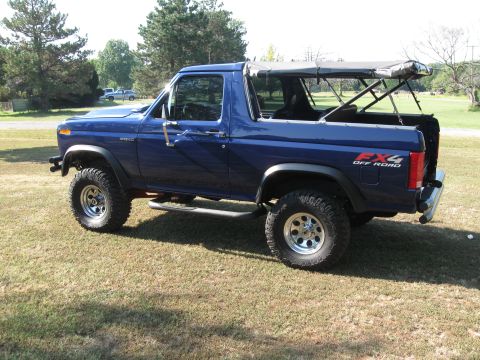 1982 Ford Bronco - This blue Ford Bronco is shown from the side with its soft top partially deployed.