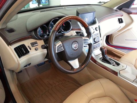 2008 Cadillac CTS - The interior of a Cadillac features tan leather seats, wood accents, and a central infotainment screen.