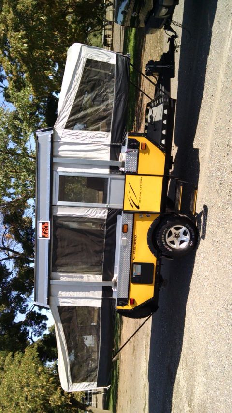 1985 Jeep CJ7 - Pop-up camper trailer with 'Fleetwood' branding is set up outdoors.