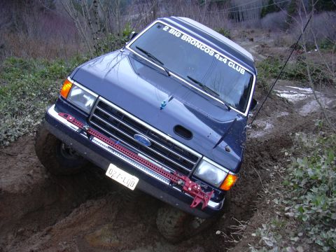 1991 Ford Bronco - This 1991 Ford Bronco is navigating a challenging muddy terrain, displaying a club sticker on its windshield.