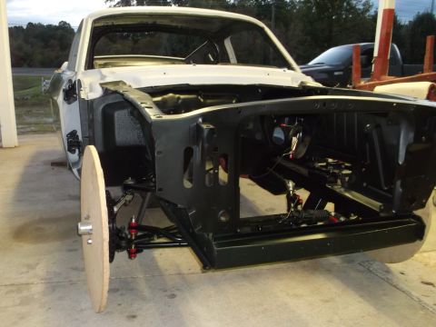 1967 Ford Mustang - Front view of a 1967 Ford Mustang undergoing restoration, with its chassis and engine bay exposed.