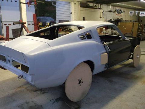 1967 Ford Mustang - A 1967 Ford Mustang is undergoing restoration, showing its bodywork and temporary wooden wheels.