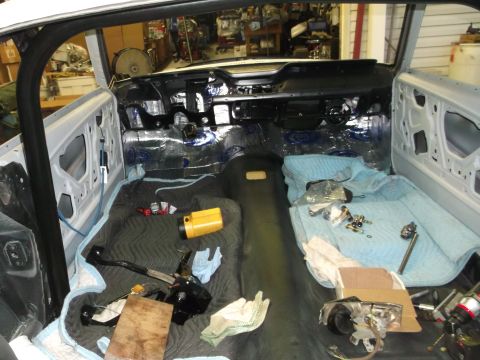 1967 Ford Mustang - Interior view of a 1967 Ford Mustang undergoing restoration, showing sound deadening material and various parts laid out.