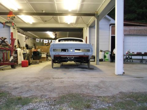 1967 Ford Mustang - Rear view of a 1967 Ford Mustang in a garage, appearing to be in the process of restoration.