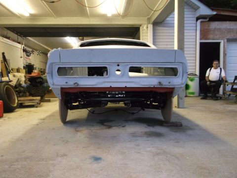 1967 Ford Mustang - A car body sits in a garage, its rear end exposed, awaiting restoration.