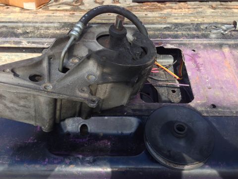 1979 Ford Bronco - A disassembled power steering pump assembly is shown resting on the vehicle's frame.