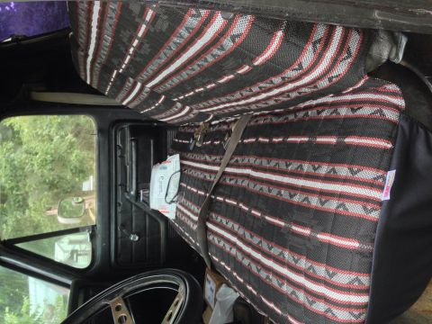 1979 Ford Bronco - The interior of a vehicle features distinctive patterned seat covers and a view of the dashboard and side window.