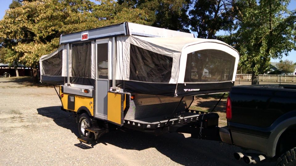 Yellow and gray pop-up camper trailer towed by black truck