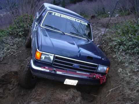 1991 Ford Bronco - A blue 1991 Ford Bronco navigates a steep, muddy off-road trail.