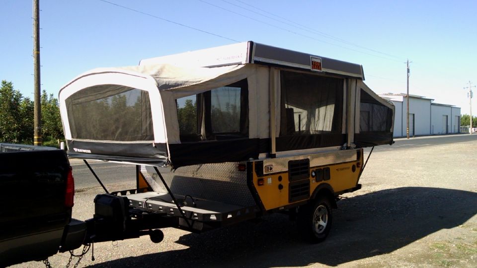 Pop-up camper trailer hitched to a dark-colored truck, parked outdoors