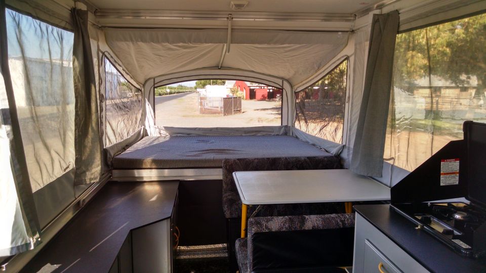 Interior view of pop-up camper with bed, table, and stove