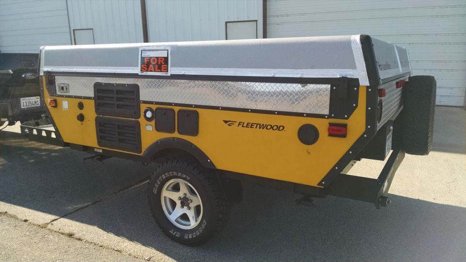 Yellow Fleetwood camper trailer with a 'For Sale' sign on top