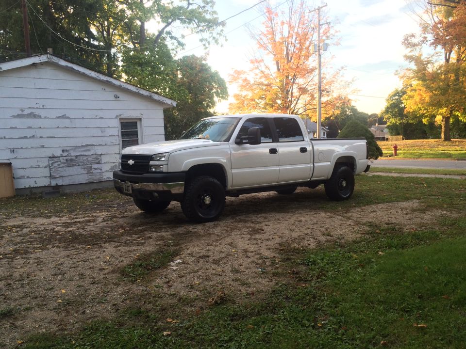 White 2006 Chevrolet Silverado 2500 pickup truck parked in a yard next to a white shed