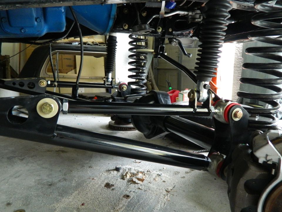 Black suspension parts and coil springs under a vehicle, with a blue differential visible