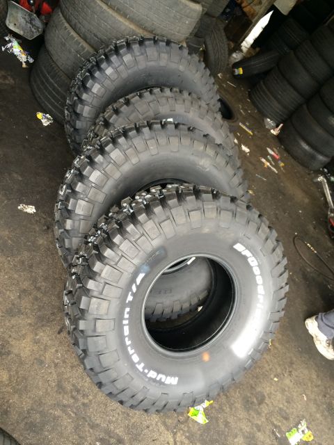 1990 Ford Bronco - Four BFGoodrich Mud-Terrain T/A off-road tires lean stacked together on a tire-shop floor.