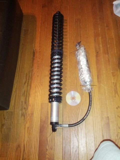 1979 Ford F-150 - A coilover shock absorber assembly with a remote reservoir hose is laid out on a wooden floor.