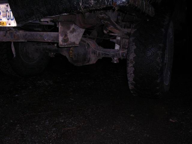 Rear axle, leaf springs, and tire of a truck. License plate visible