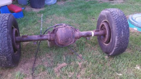 1979 Ford Bronco - Rear axle assembly with two wheels resting on grass.