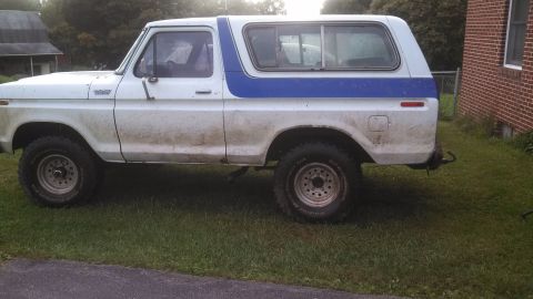 1979 Ford Bronco - This 1978 Ford Bronco is seen from the side, parked on a grassy area next to a brick building.