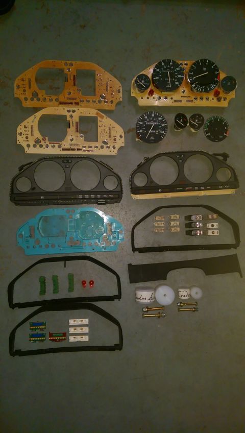 1989 BMW 3 Series - Various BMW instrument cluster components, including circuit boards, gauges, and bezels, are displayed on a floor.