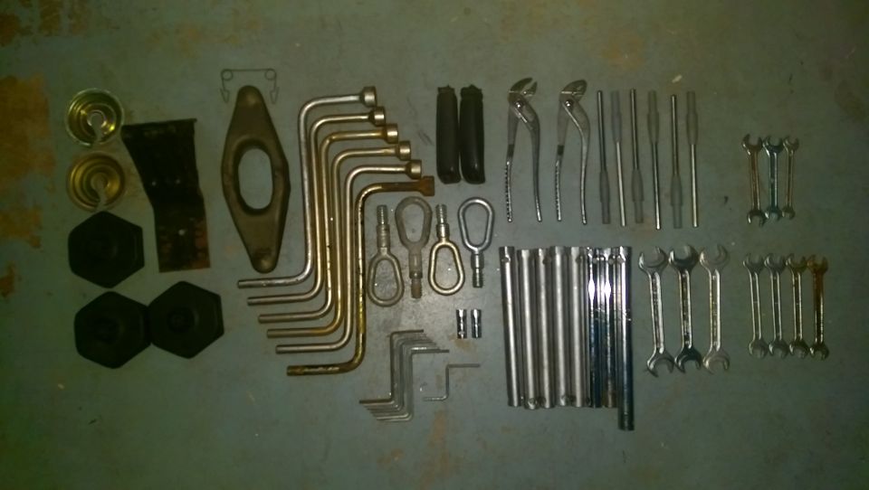 Collection of wrenches, pliers, sockets, and other assorted tools laid out on a gray surface