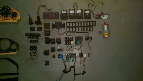 1989 BMW 3 Series - Various automotive electrical components, including switches, relays, and a gauge cluster, are spread out on a concrete surface.
