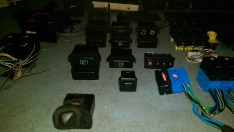 1989 BMW 3 Series - Various automotive interior switches and connectors are laid out on a surface, some with visible wiring.