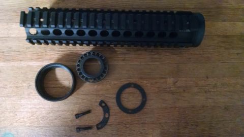 1996 Ford Bronco - Disassembled gun parts are laid out on a wooden surface, including a barrel shroud and various rings and screws.
