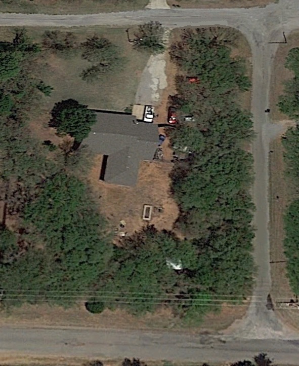 Aerial view of two red vehicles and a white vehicle parked near a house