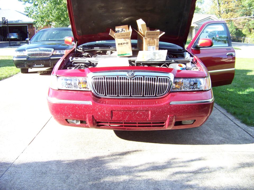 Red Mercury Grand Marquis with hood open, chrome grille, and DEPO headlight boxes inside