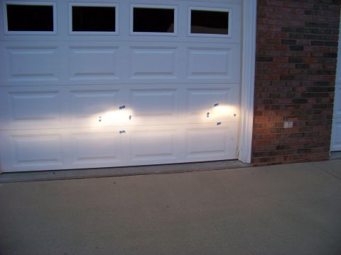 1999 Mercury Grand Marquis - Headlights are taped to a garage door, casting light patterns on the surface.
