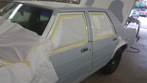 1991 Ford LTD Crown Victoria - A car is being prepped for painting, with masking tape covering the windows.