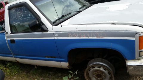 1991 Ford LTD Crown Victoria - Side view of a white and blue pickup truck with handwritten markings and a missing wheel.