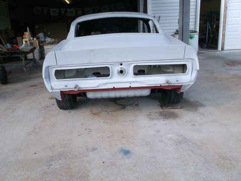 1967 Ford Mustang - Rear view of a 1967 Ford Mustang undergoing restoration, showing its primer finish and empty taillight housings.