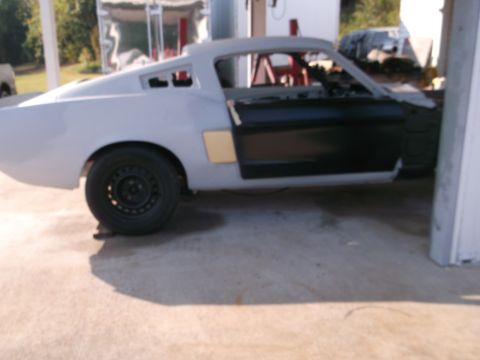 1967 Ford Mustang - This classic Mustang fastback is in the process of being restored, with its body in primer and interior components visible.