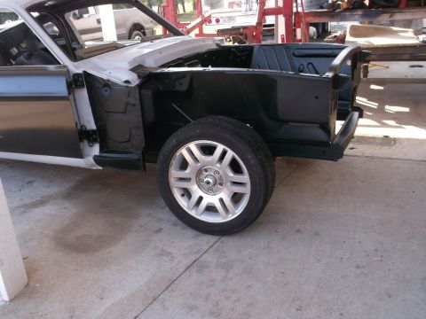1967 Ford Mustang - A car body is being worked on in a garage, with the front wheel and part of the interior visible.