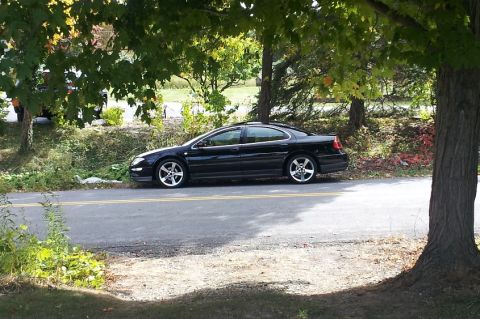 2002 Chrysler 300M - Side view of a black 2002 Chrysler 300M parked on the shoulder of a road.