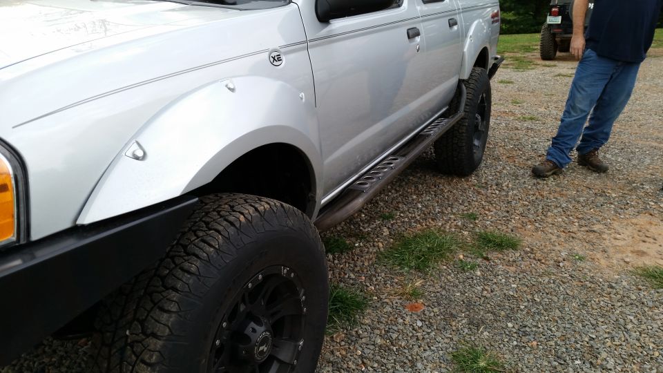 Silver 2003 Nissan Frontier pickup truck with aftermarket side steps and fender flares