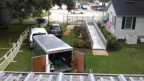 1994 Ford Bronco - An open trailer and an SUV are parked in a grassy area next to a building with an accessibility ramp.