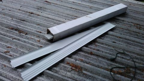 1994 Ford Bronco - Two metal trim pieces and a cardboard tube are laid out on a corrugated metal roof.