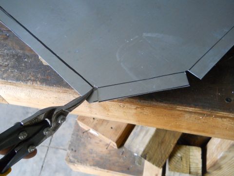 1992 Ford Bronco - Tin snips cut through a sheet of metal marked with cutting lines on a wooden surface.