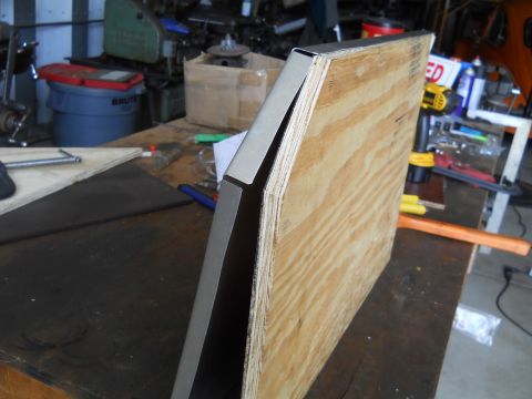1992 Ford Bronco - A piece of metal trim is affixed to a plywood construction on a workbench.